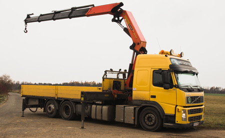 Žluté nákladní vozidlo Volvo s hydraulickou rukou v terénu